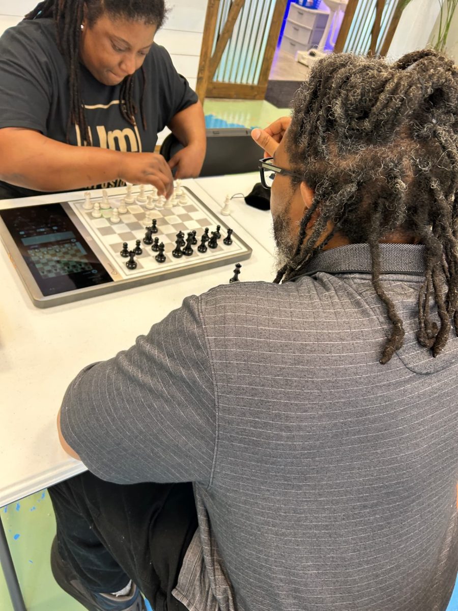Two adults playing chess on an electronic board